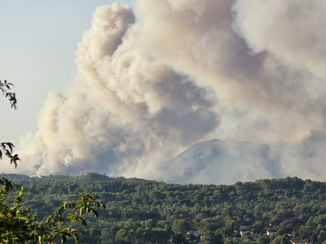 Incendie de forêt en Provence Verte, avec un important panache de fumée au-dessus des collines boisées.
